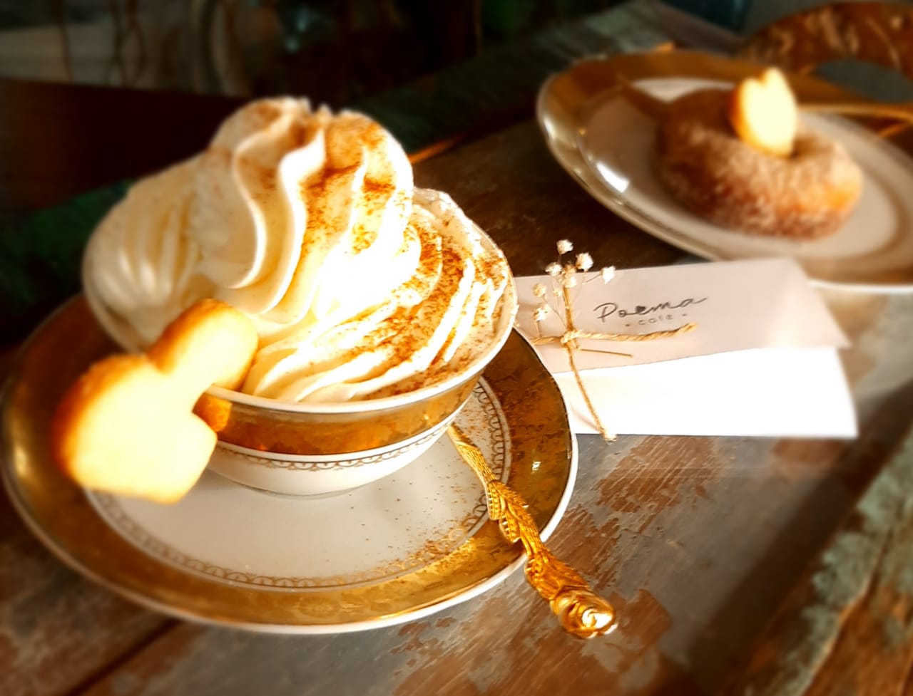 Café com especial em caneca grande com desenho na espuma, e um biscoito em formato de coração